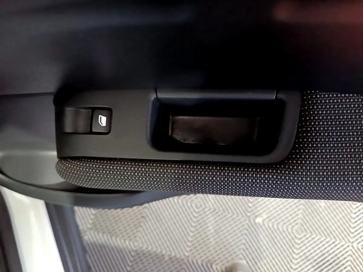 Gros plan sur la poignée intérieure et commande de lève-vitre côté gauche du Citroën C3 Aircross blanc.