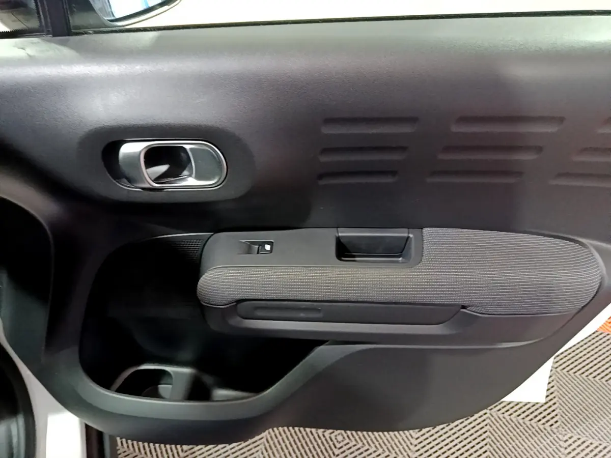 Vue rapprochée de la porte intérieure côté droit du Citroën C3 Aircross blanc, avec poignée argentée et accoudoir tissu.