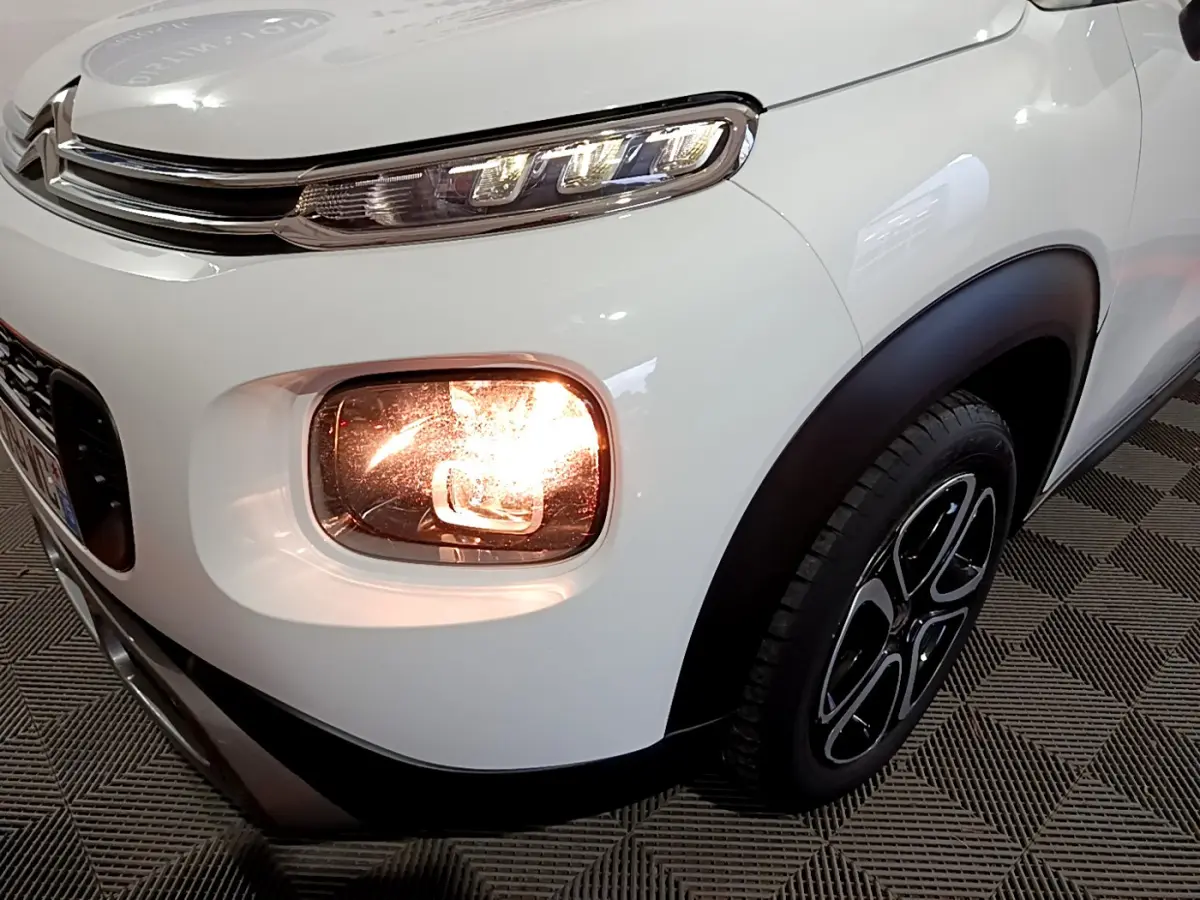 Gros plan sur l'avant droit blanc du Citroën C3 Aircross 2019 avec phare antibrouillard allumé et jante noire.