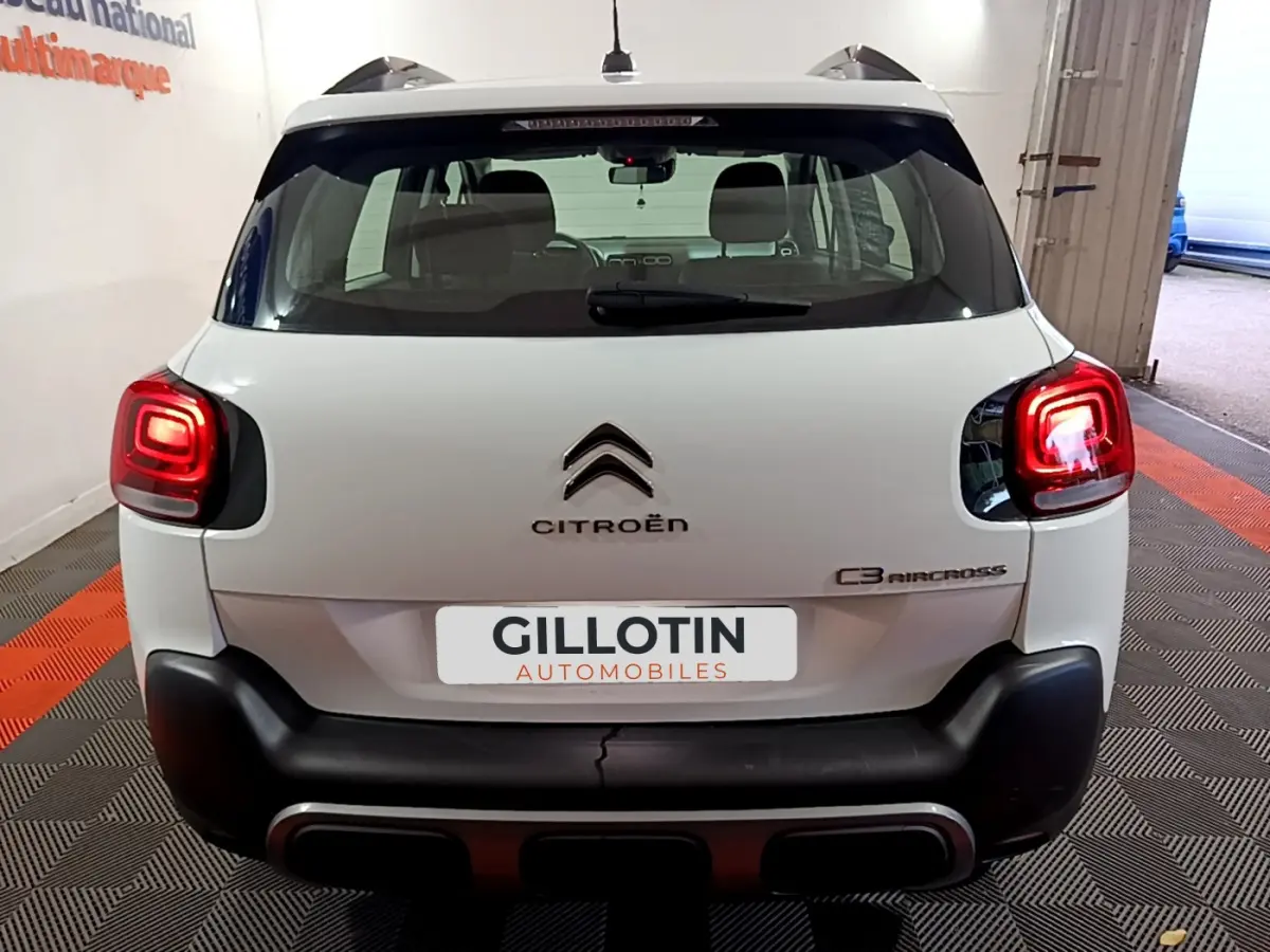 Vue arrière d'un Citroën C3 Aircross blanc avec feux arrière allumés dans un garage.