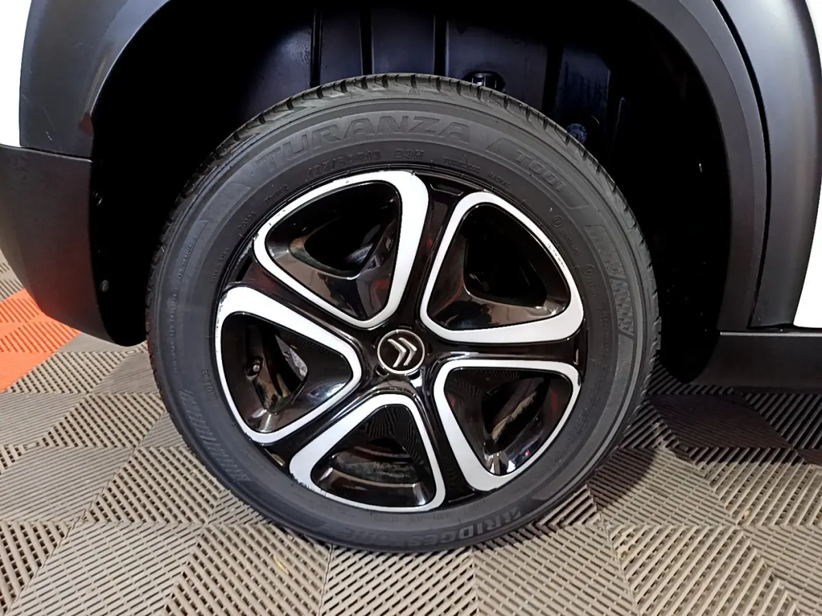 Gros plan sur la roue avant droite noire et argentée du Citroën C3 Aircross blanc de 2019.