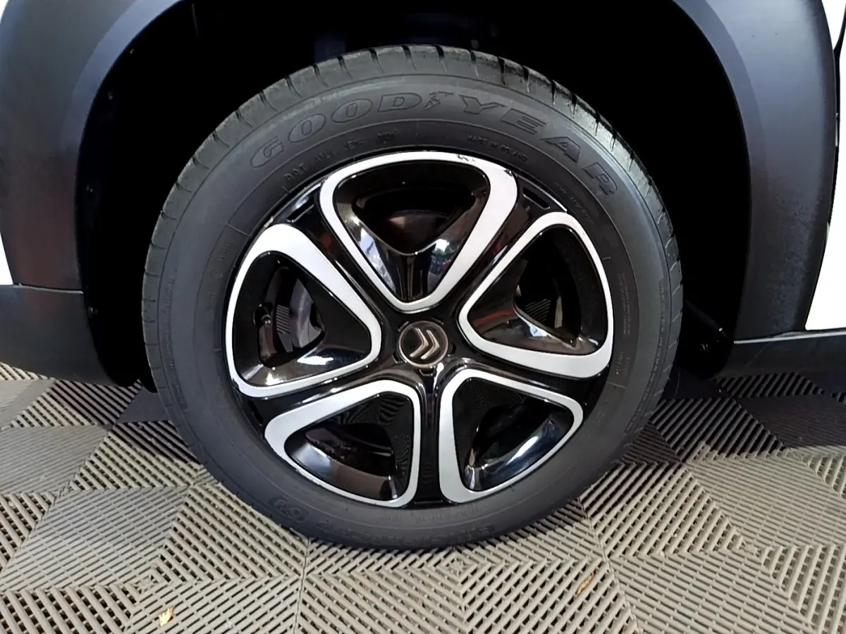 Gros plan sur la roue avant droite du Citroën C3 Aircross blanc avec jante noire et argentée au design distinctif.