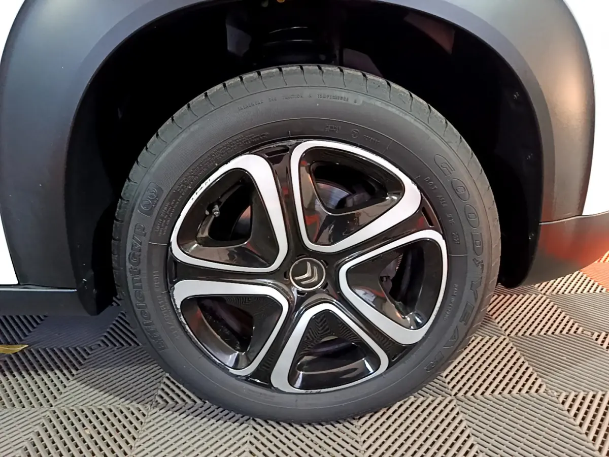 Gros plan sur la roue avant droite du Citroën C3 Aircross blanc, mettant en valeur la jante noire et argentée distinctive.