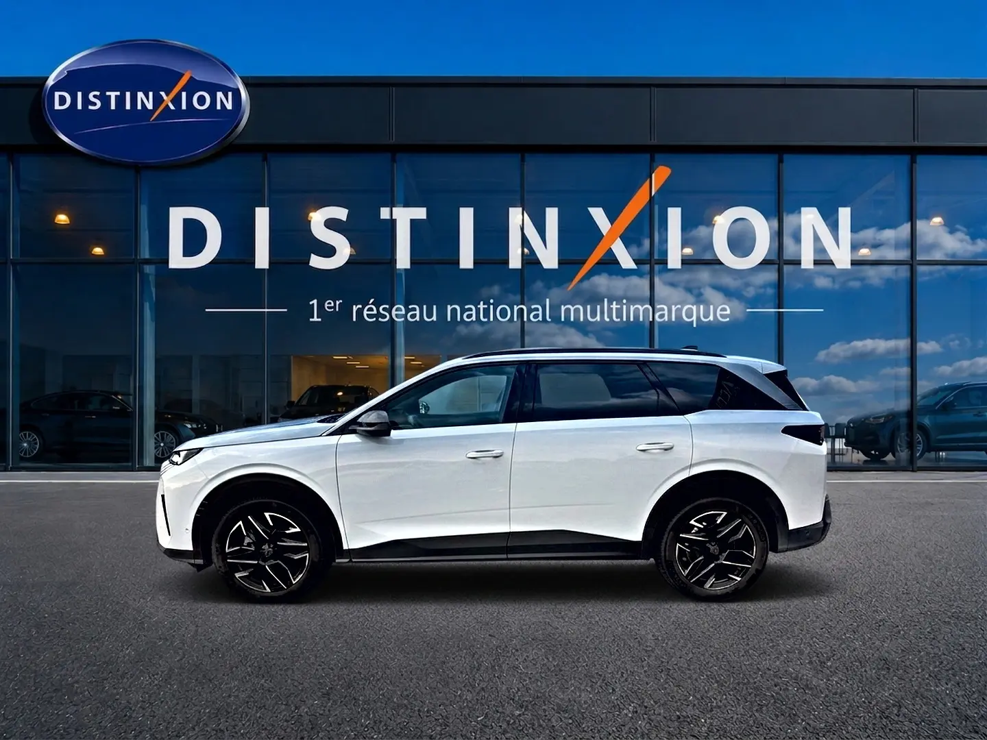 Peugeot 5008 Hybrid 145 allure e-dcs6 blanc vue de profil côté gauche devant un bâtiment vitré Distinxion.