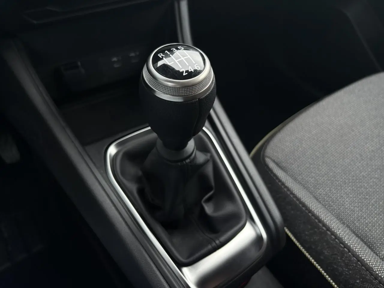 Le levier de vitesse manuel noir avec pommeau argenté et coutures visibles dans l'habitacle du Renault Captur TCE 100 Techno.