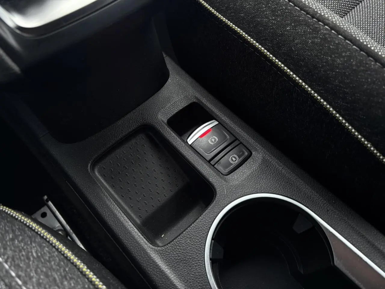 Gros plan sur la console centrale du Renault Captur TCE 100 Techno 2025, montrant frein à main électrique et rangement noir.