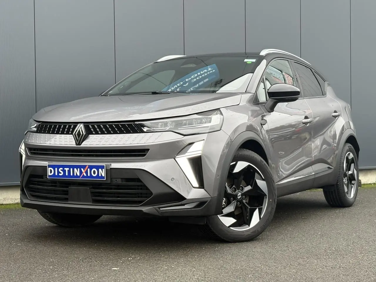 Renault Captur TCE 100 Techno gris Cassiopée avec toit noir, vu en 3/4 avant droit, jantes alu diamantées noires visibles.
