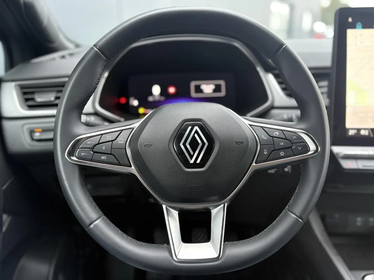 Gros plan sur le volant noir du Renault Captur TCE 100 Techno 2025 avec commandes intégrées et tableau de bord numérique flou.