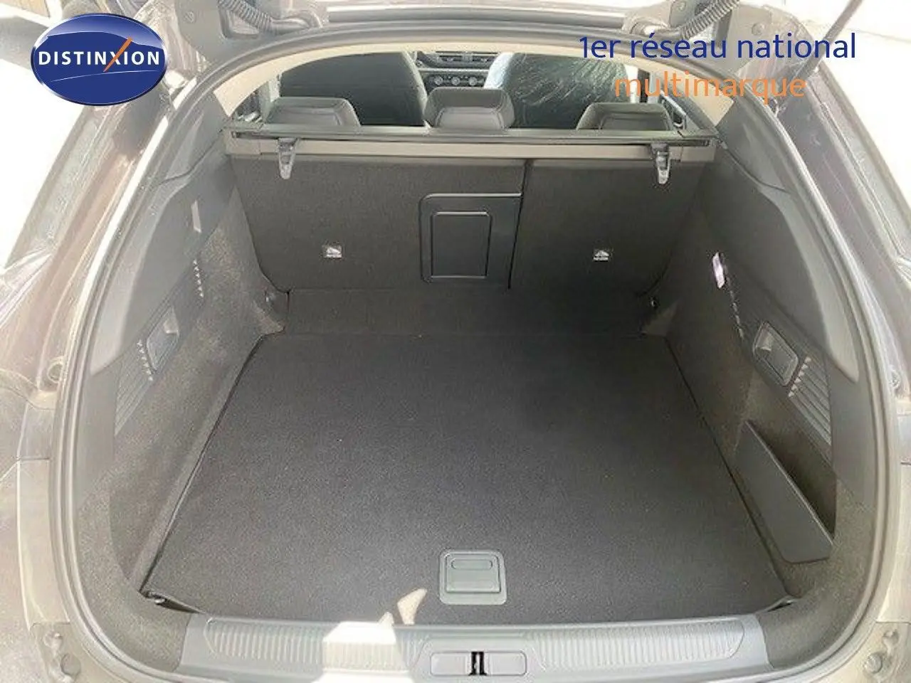 Coffre ouvert vu de l’arrière d’une Citroën C5 X gris thorium métal, espace de chargement spacieux et bien fini.