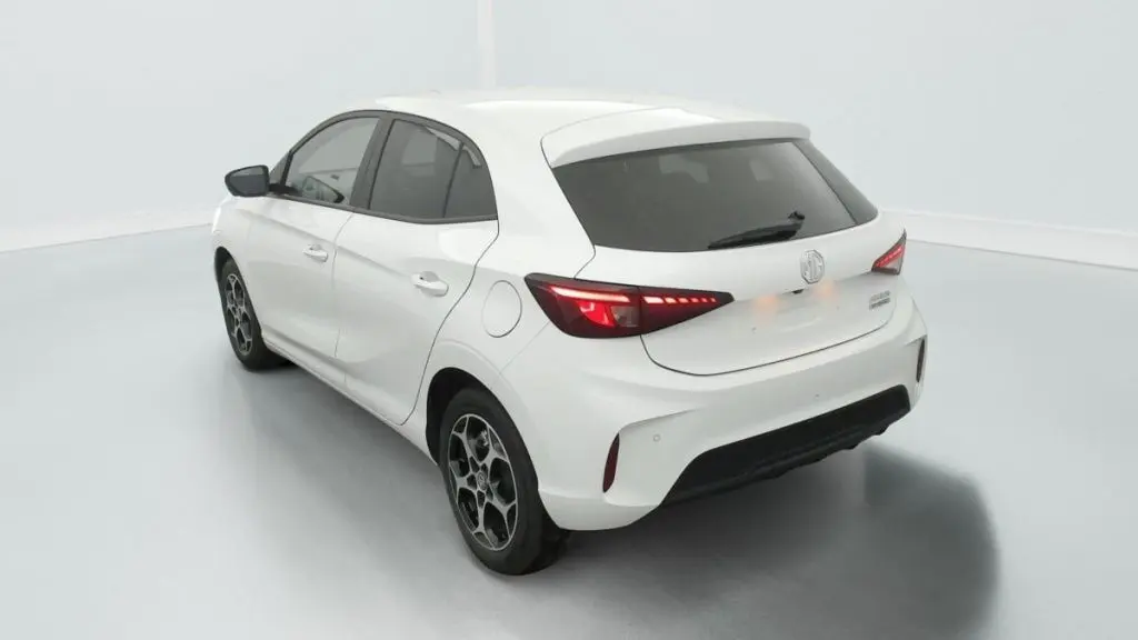 Vue 3/4 arrière gauche de la MG3 1.5 L HYBRID+ 195 CH Luxury en blanc Dover avec feux arrière allumés et jantes noires.