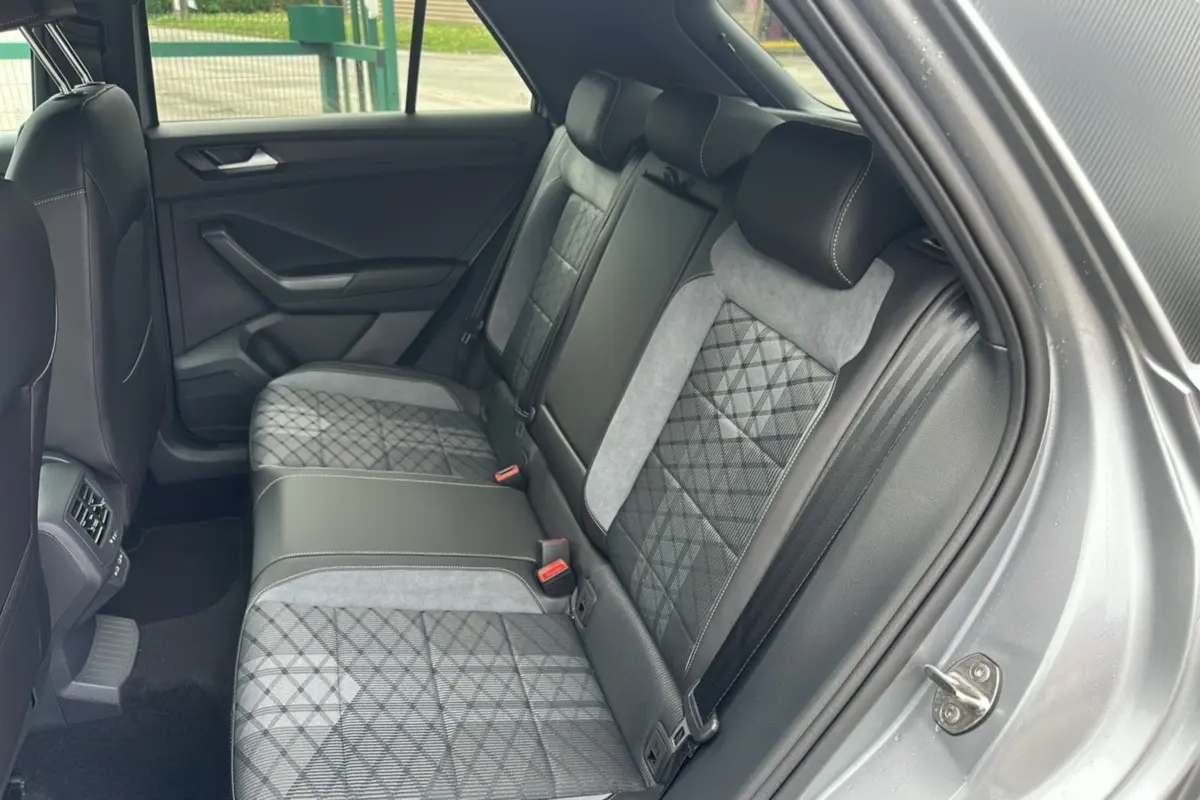 Vue intérieure arrière droite du Volkswagen T-Roc 2025 gris pyrite, sièges arrière en tissu et cuir avec surpiqûres contrastées.