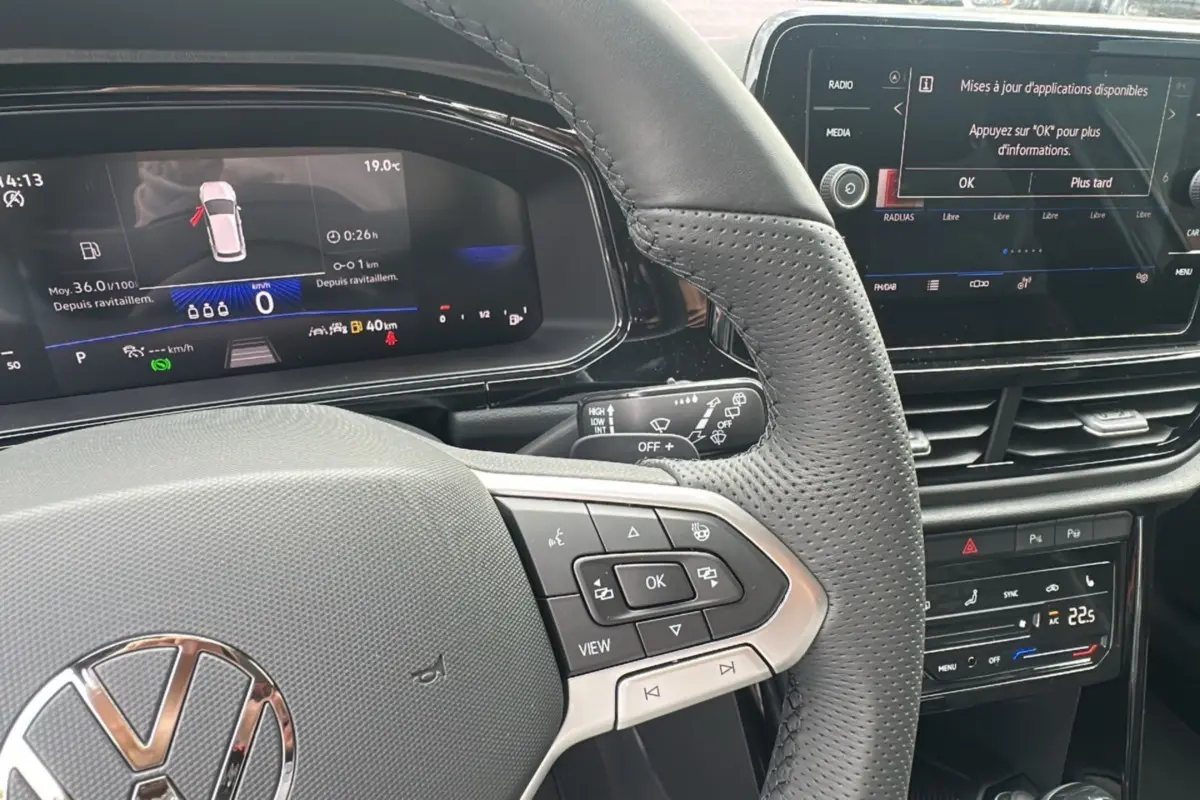 Vue rapprochée du volant et tableau de bord numérique du Volkswagen T-Roc gris pyrite avec commandes multifonctions et écran tactile.
