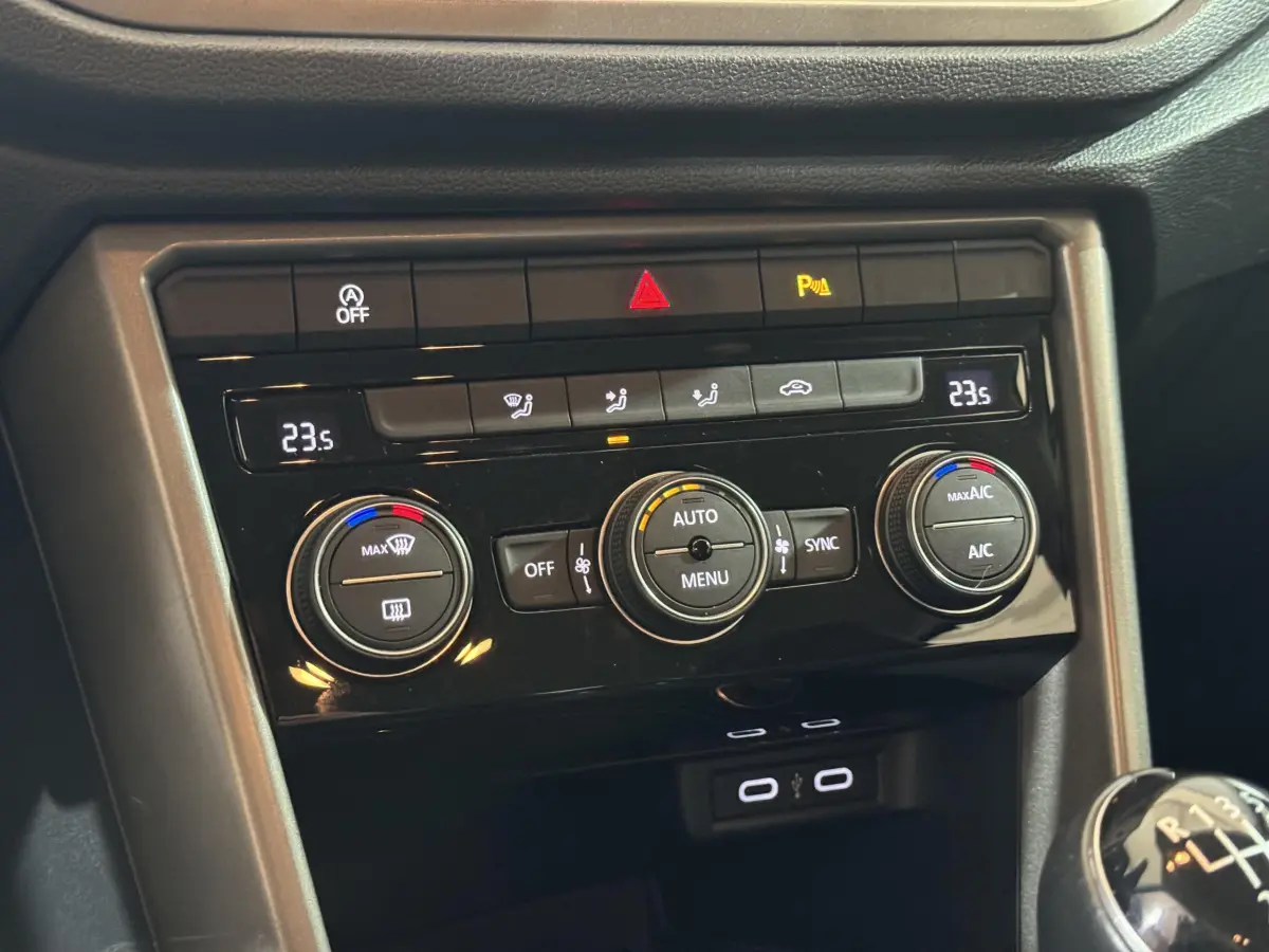 Vue rapprochée du tableau de bord du Volkswagen T-Roc gris foncé, montrant la climatisation digitale et la boîte manuelle.