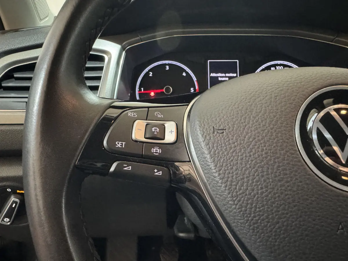 Gros plan sur le volant cuir côté gauche du Volkswagen T-Roc 2021 avec commandes multifonctions et tableau de bord partiellement visible.