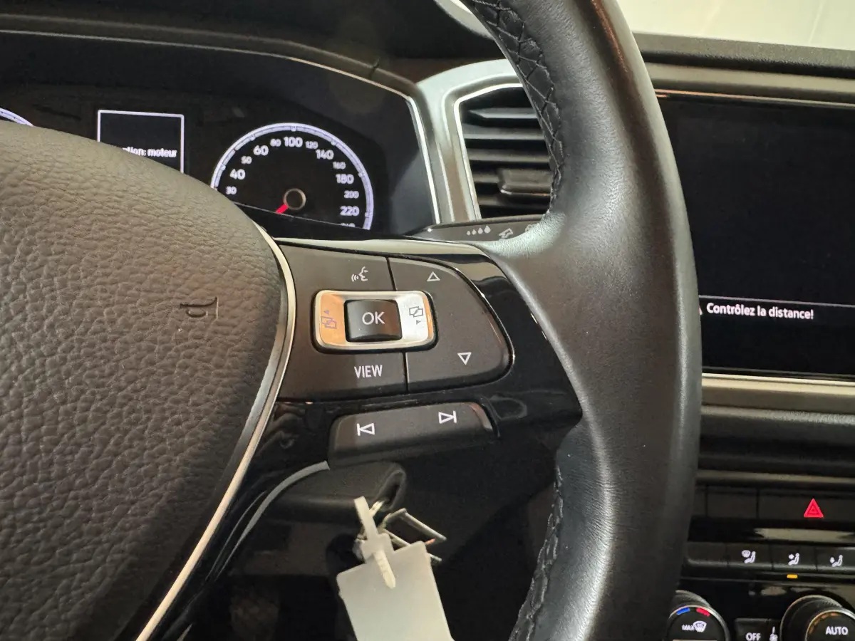 Gros plan sur le volant cuir noir et le tableau de bord numérique du Volkswagen T-Roc 1.6 TDI 2021, intérieur gris foncé.