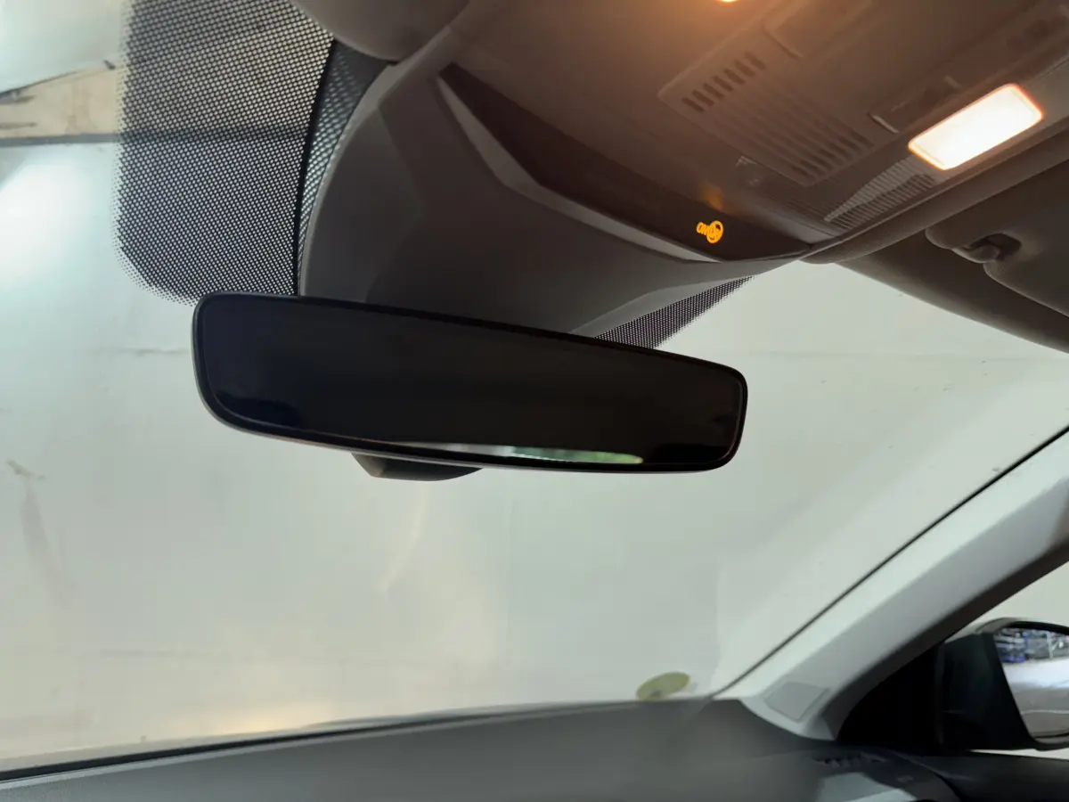 Vue intérieure centrée sur le rétroviseur intérieur d'un Volkswagen T-Roc gris foncé, avec plafonnier allumé.