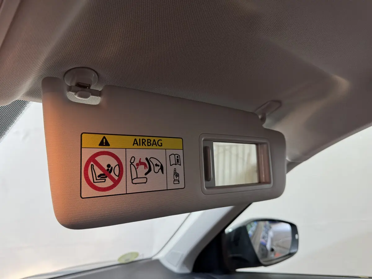 Détail du pare-soleil côté conducteur avec miroir intégré et avertissement airbag dans un Volkswagen T-Roc gris foncé.