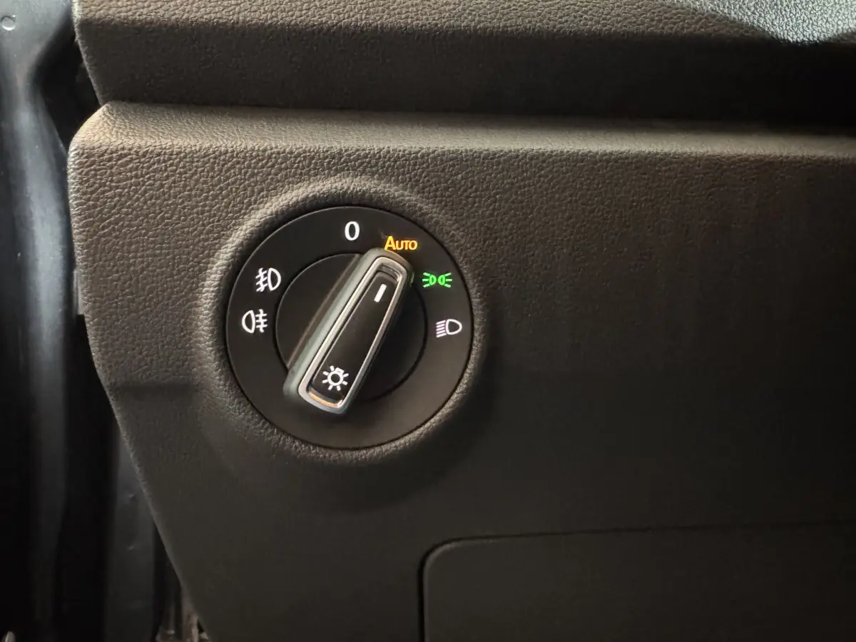 Gros plan sur le bouton de commande des phares du Volkswagen T-Roc 1.6 TDI 115 Lounge Business, intérieur noir.