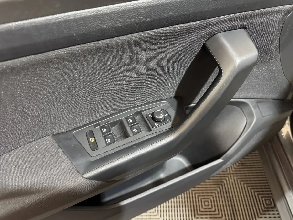 Vue rapprochée de la porte avant gauche du Volkswagen T-Roc gris foncé, montrant les commandes des vitres et rétroviseurs.