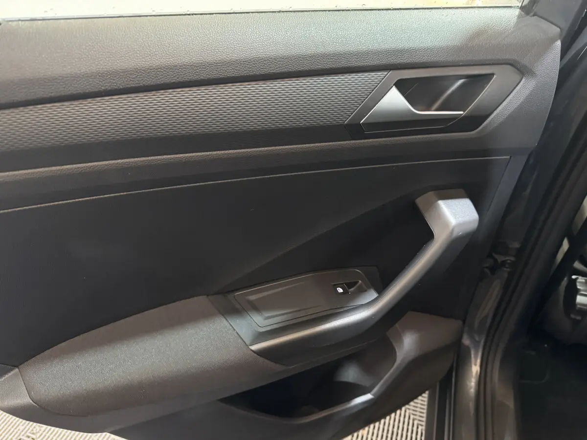 Vue rapprochée de la porte avant droite gris foncé du Volkswagen T-Roc 1.6 TDI 115 Lounge Business avec poignée et bouton de verrouillage.