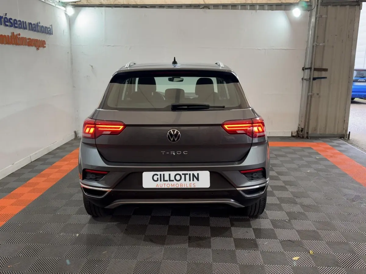 Vue arrière d’un Volkswagen T-Roc gris foncé avec feux LED allumés dans un garage intérieur.