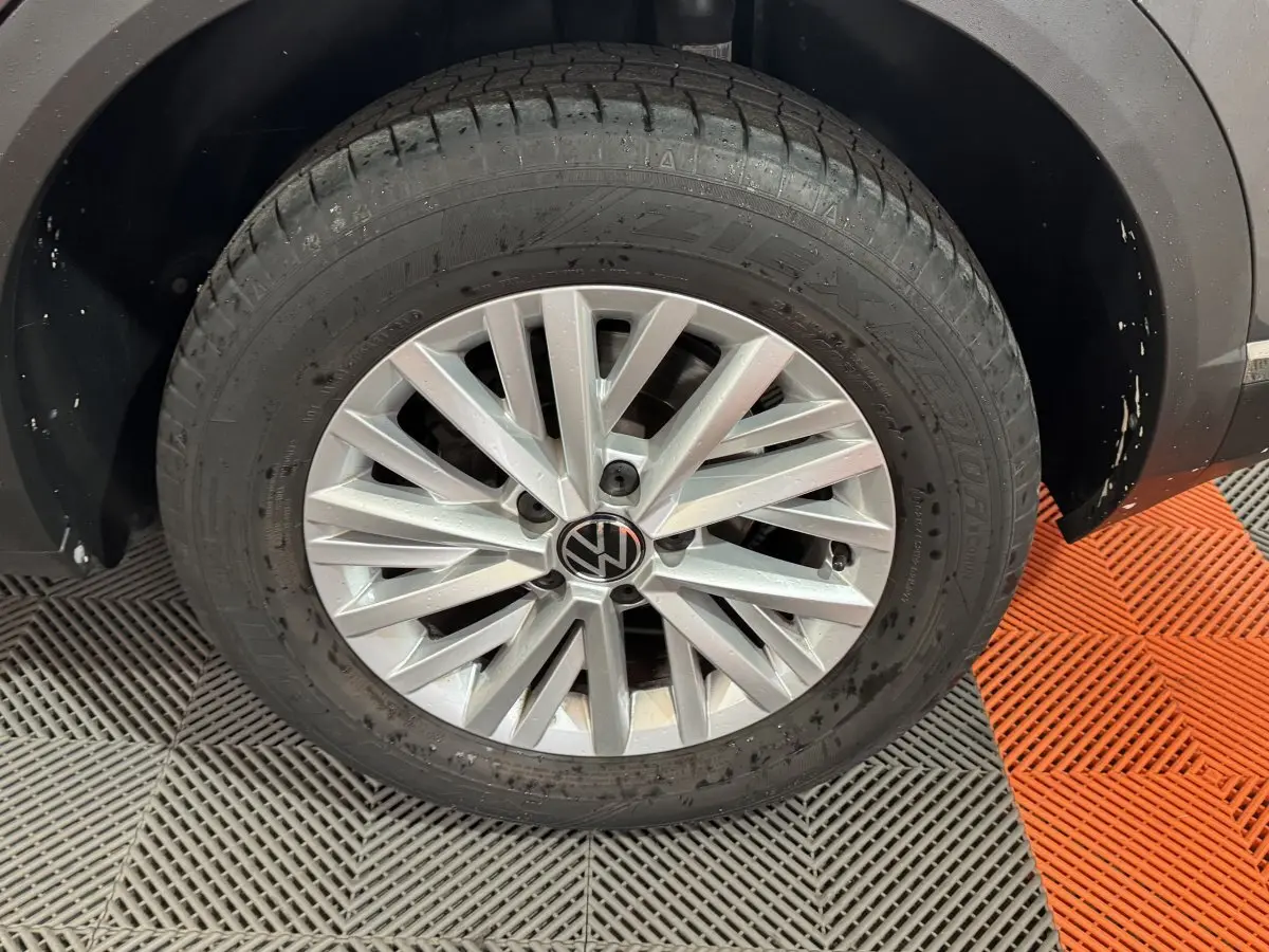 Gros plan sur la roue avant droite d’un Volkswagen T-Roc gris foncé avec jante alliage à multiples branches.