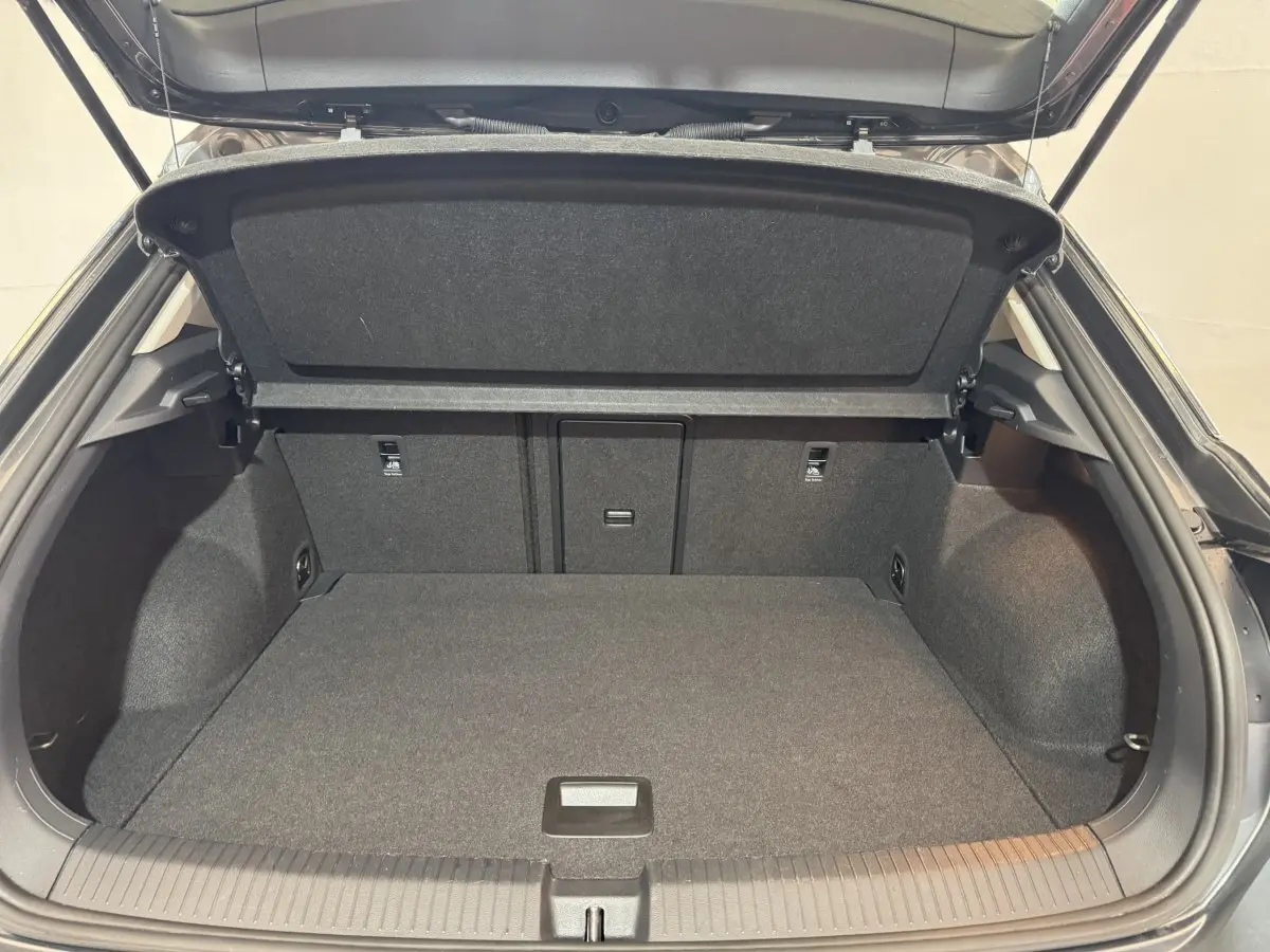 Coffre ouvert gris foncé du Volkswagen T-Roc 1.6 TDI 115 Lounge Business, vue arrière montrant l'espace de chargement vide.
