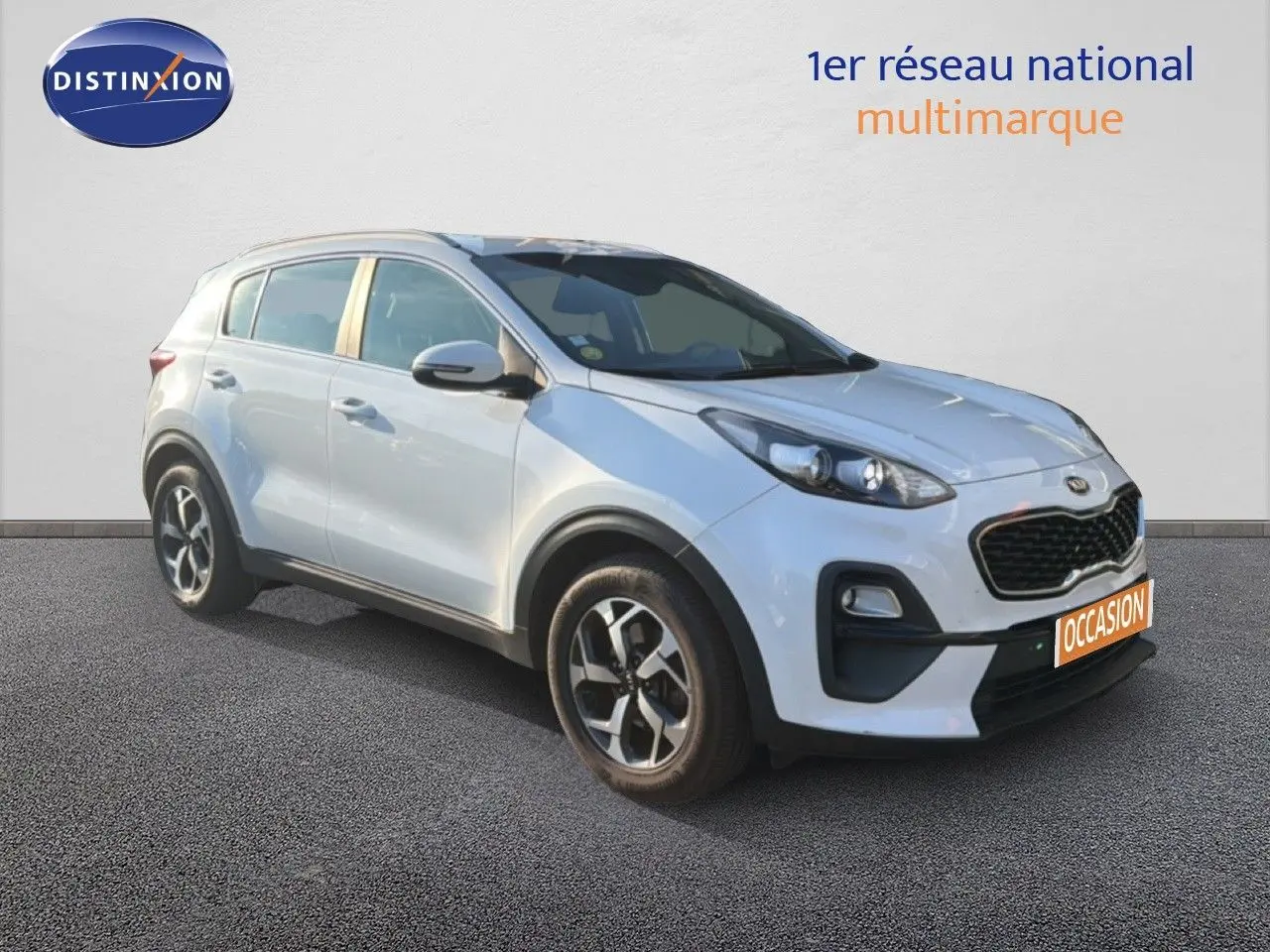 KIA Sportage blanc nacré métal en 3/4 avant droit, avec calandre noire et jantes alliage bicolores.