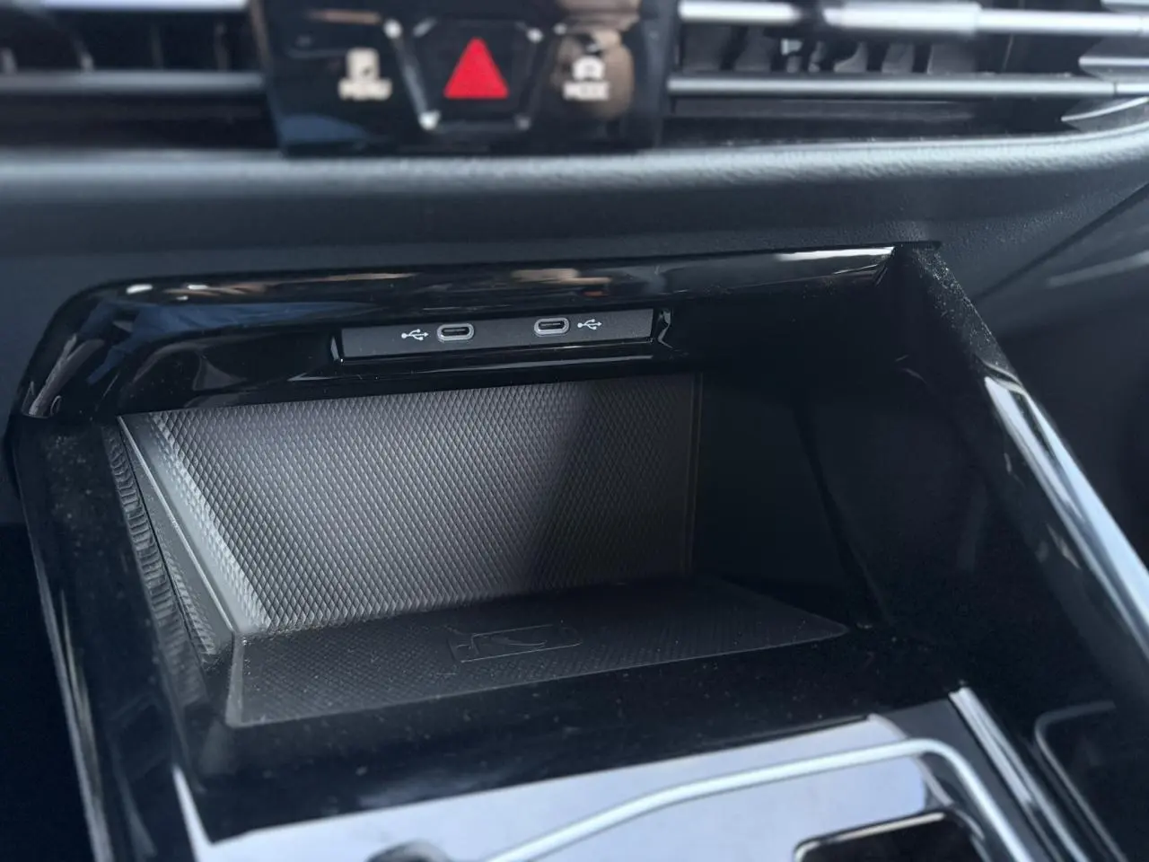 Vue rapprochée de la console centrale noire de la Volkswagen Golf 8 R-Line avec ports USB-C et surface texturée antidérapante.