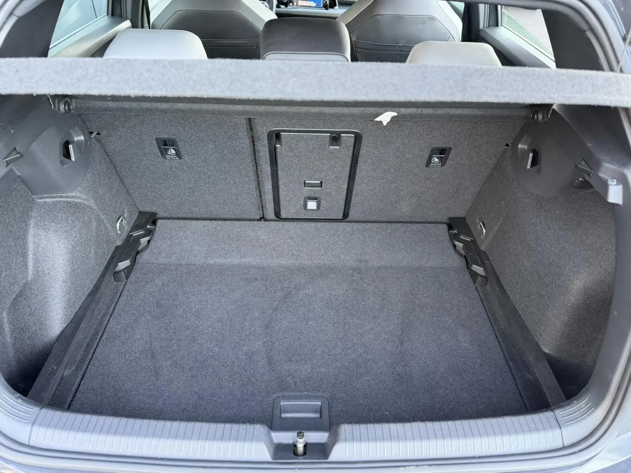 Coffre ouvert vu de l'arrière d'une Volkswagen Golf 8 Gris Urano, montrant l'espace de chargement et les sièges arrière.