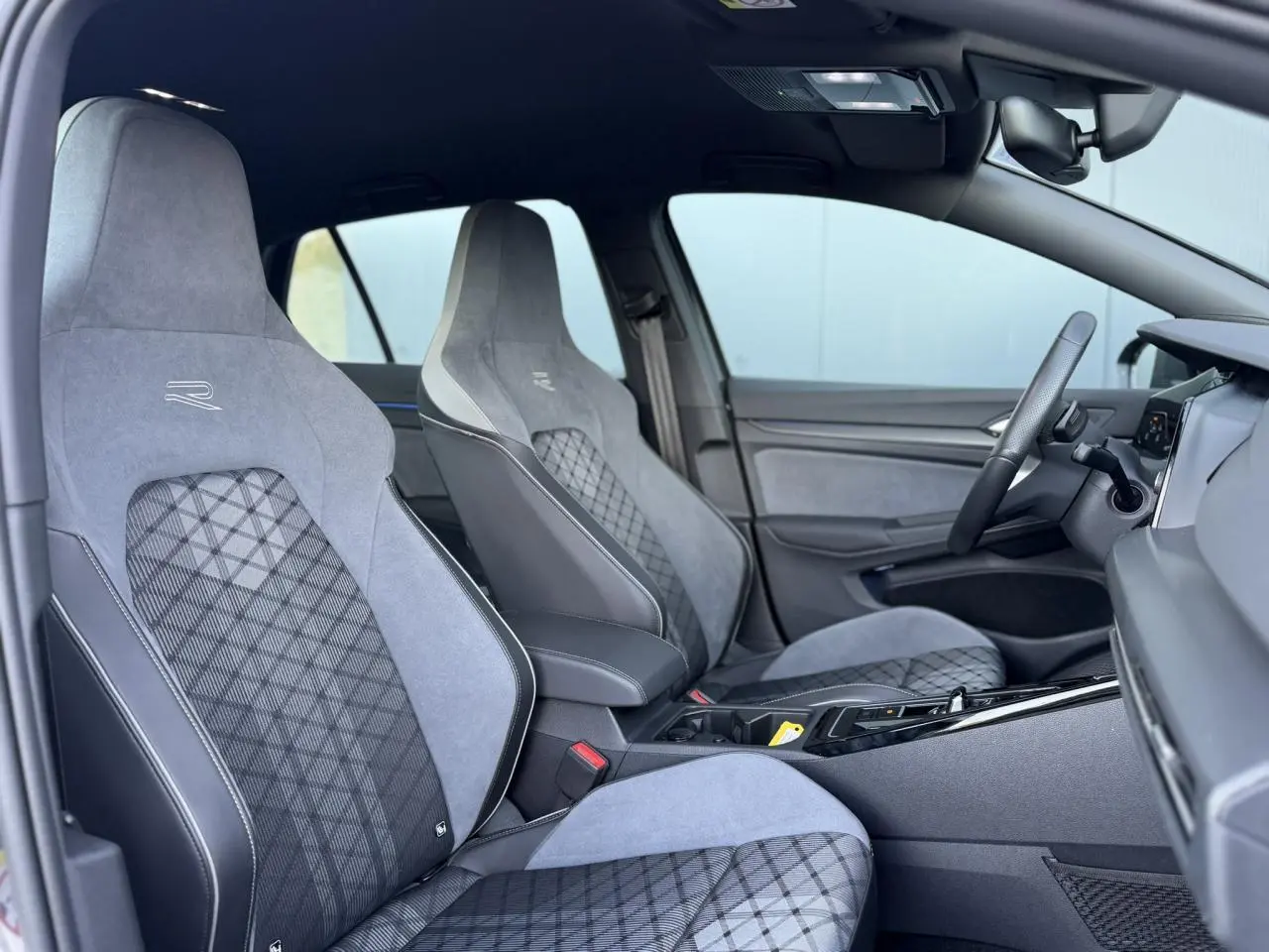 Intérieur de la Volkswagen Golf 8 R-Line 2024, vue côté droit sur sièges sport gris avec surpiqûres et volant multifonction.