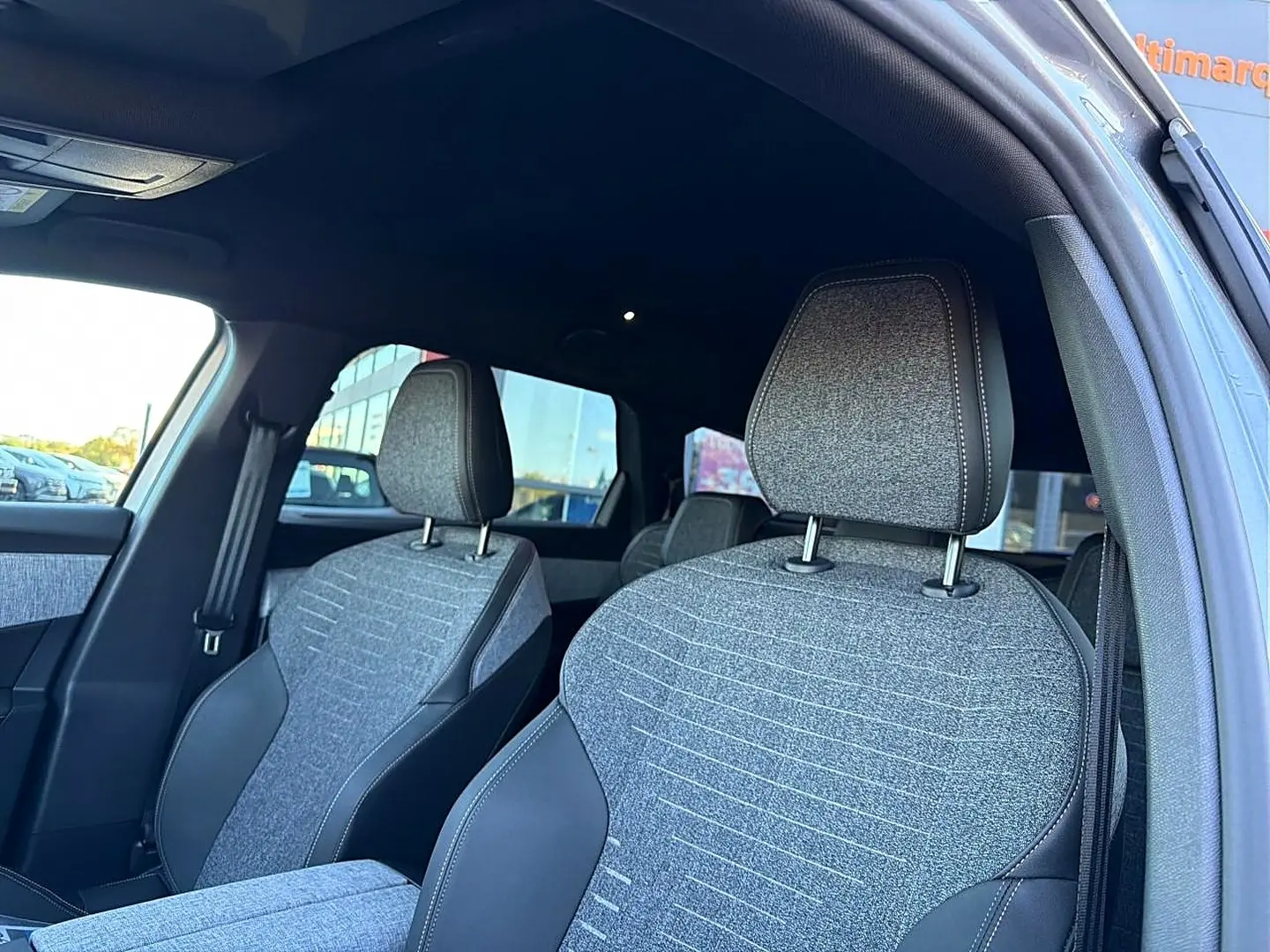 Vue intérieure côté gauche montrant les sièges avant gris tissu et cuir du Peugeot 5008 Hybrid 145 allure e-dcs6 2025.