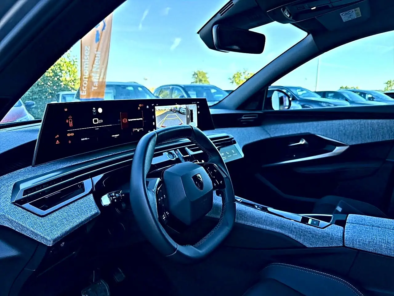 Vue intérieure côté conducteur du Peugeot 5008 Hybrid 145 allure e-dcs6 2025 avec tableau de bord numérique et tissus gris.