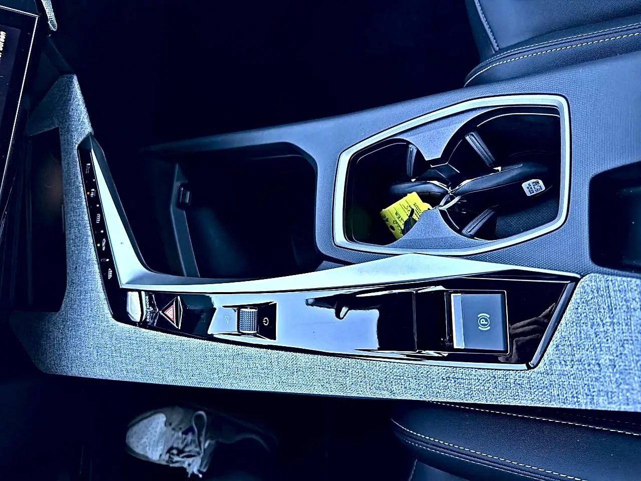Vue rapprochée de la console centrale grise et noire du Peugeot 5008 Hybrid 145 allure e-dcs6 avec porte-gobelets et commandes tactiles.