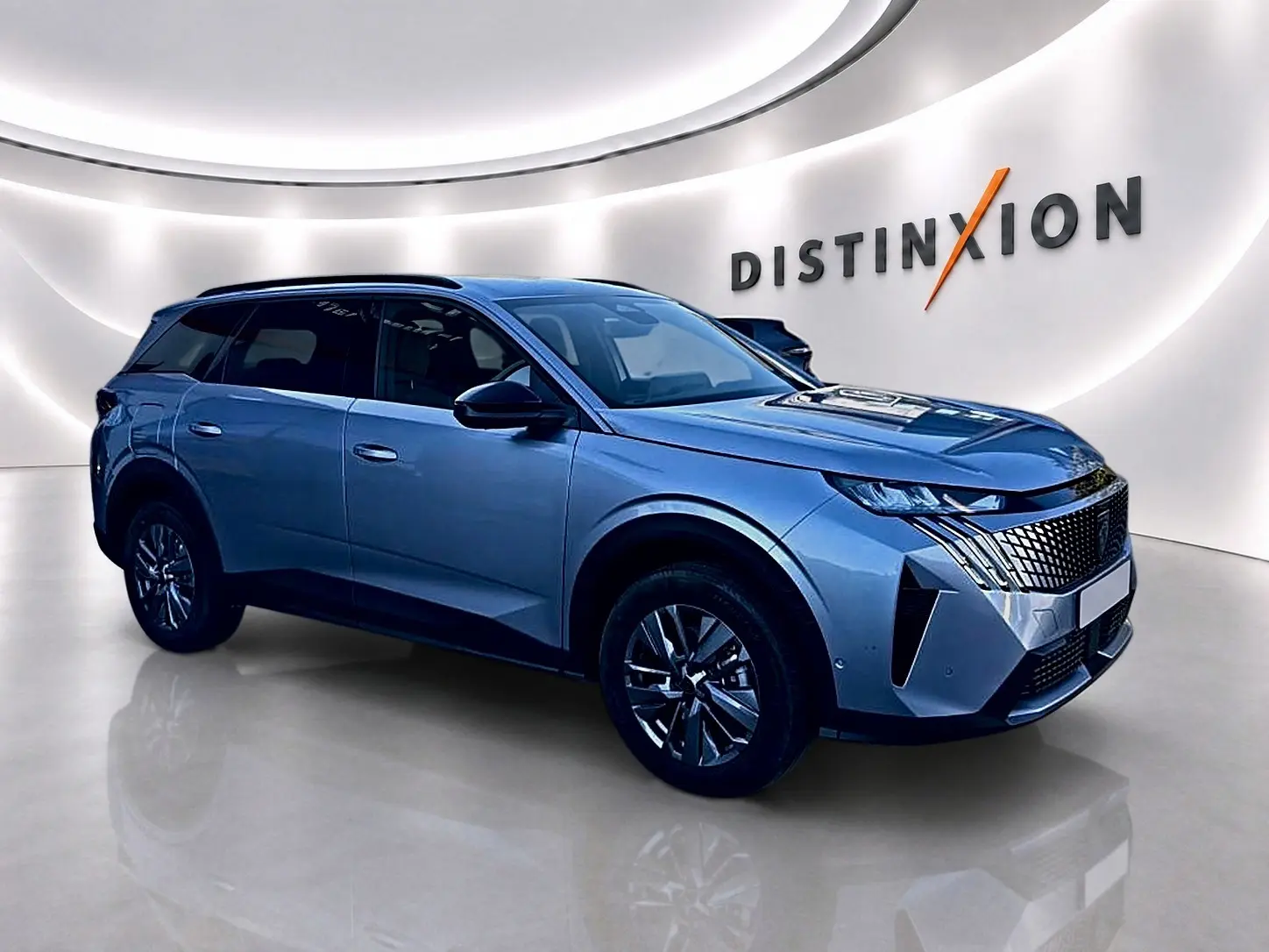 Peugeot 5008 Hybrid 145 allure e-dcs6 gris artense, vue 3/4 avant droit dans un showroom lumineux.