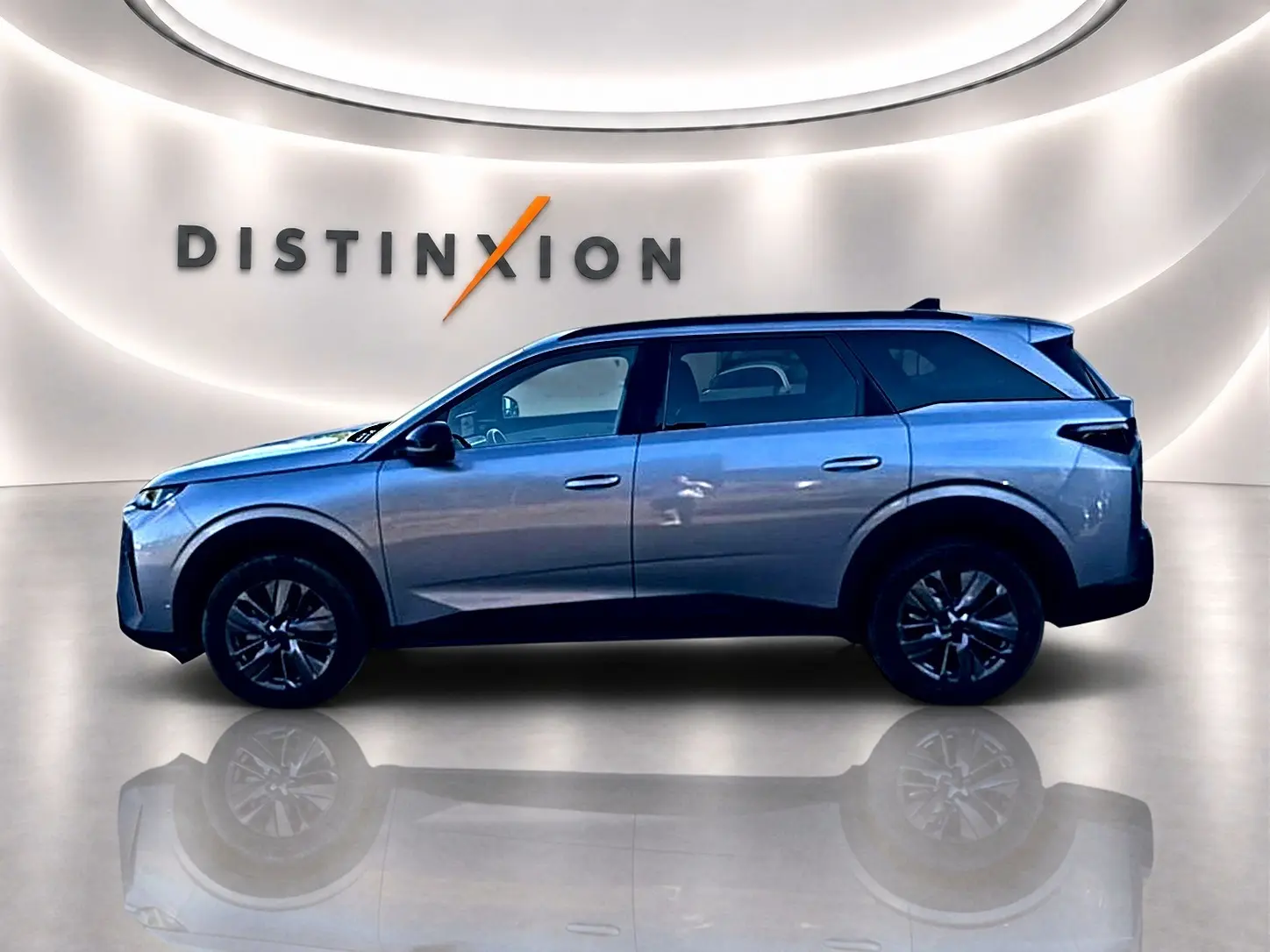 Profil droit du Peugeot 5008 Hybrid 145 allure e-dcs6 gris artense dans un showroom lumineux avec reflet au sol.