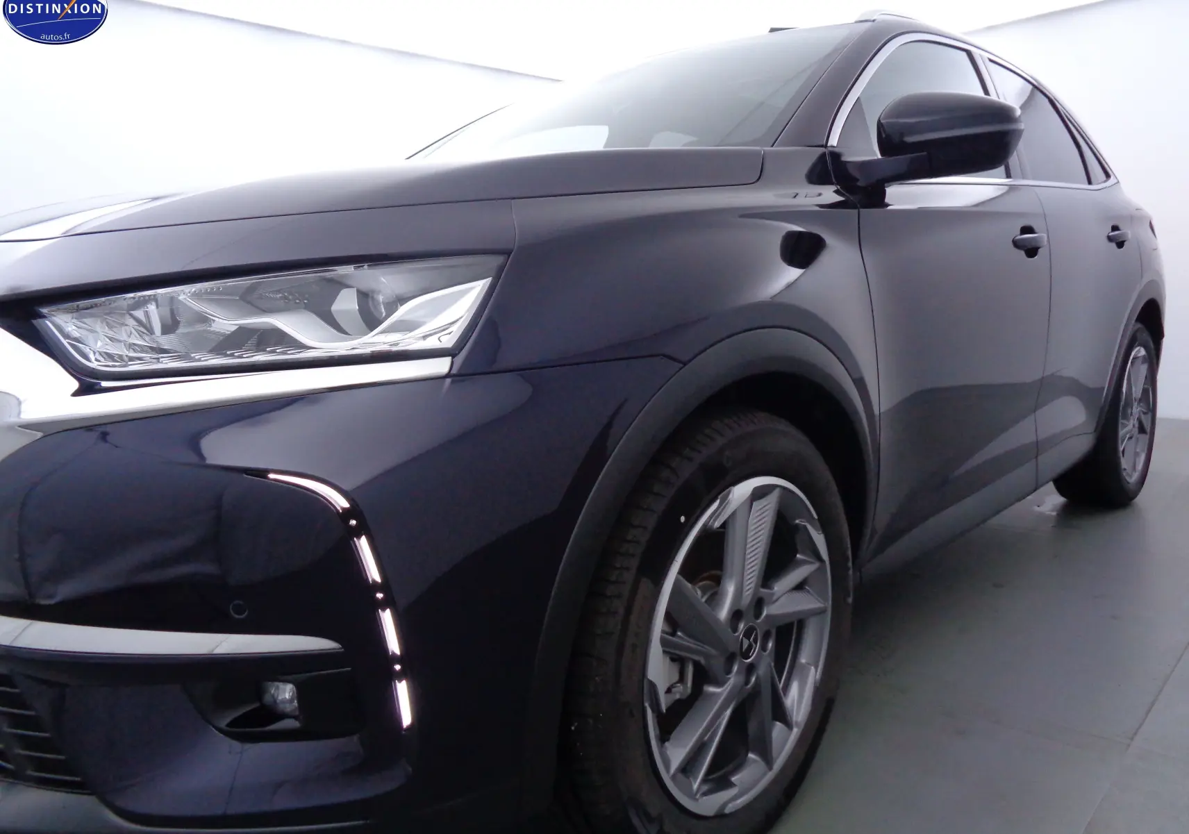 Vue 3/4 avant droit d'un DS7 Crossback hybride rechargeable bleu encre métal avec feux LED et jantes alliage.