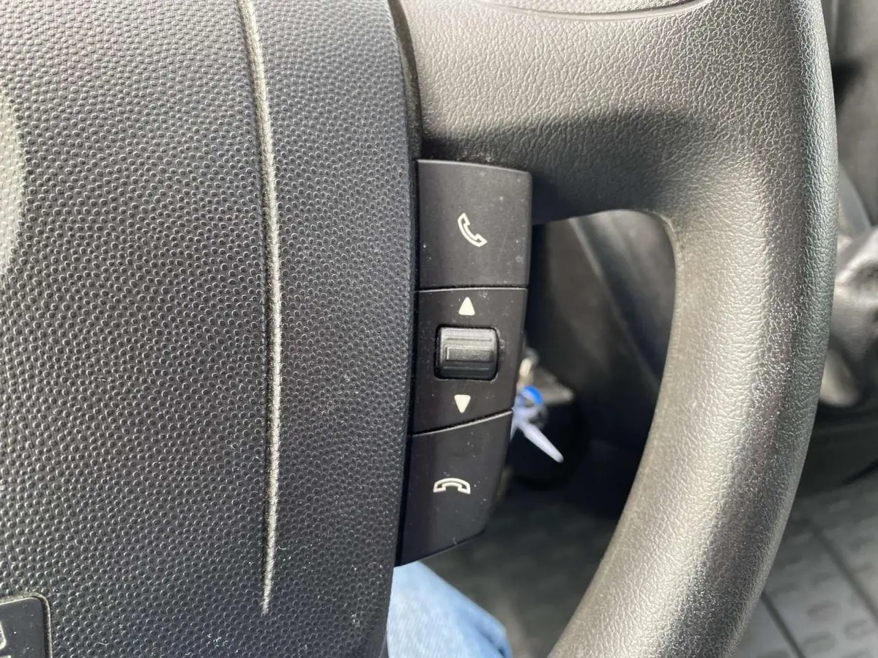 Gros plan sur les commandes téléphoniques au volant noir de l'Opel Movano Fourgon blanc, version 2022.