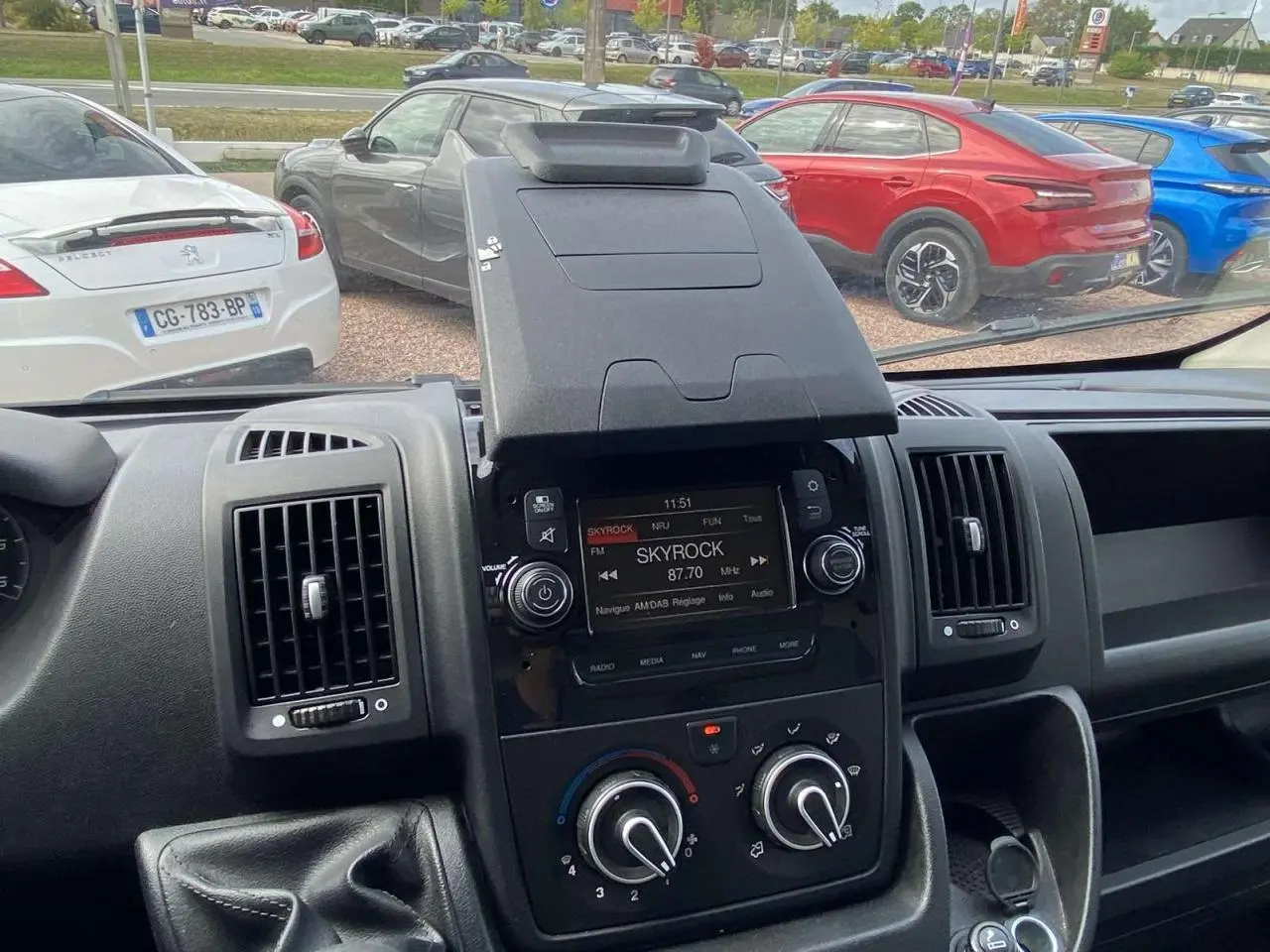 Vue intérieure du tableau de bord de l'Opel Movano Fourgon 2022 avec écran radio Skyrock et commandes de climatisation.