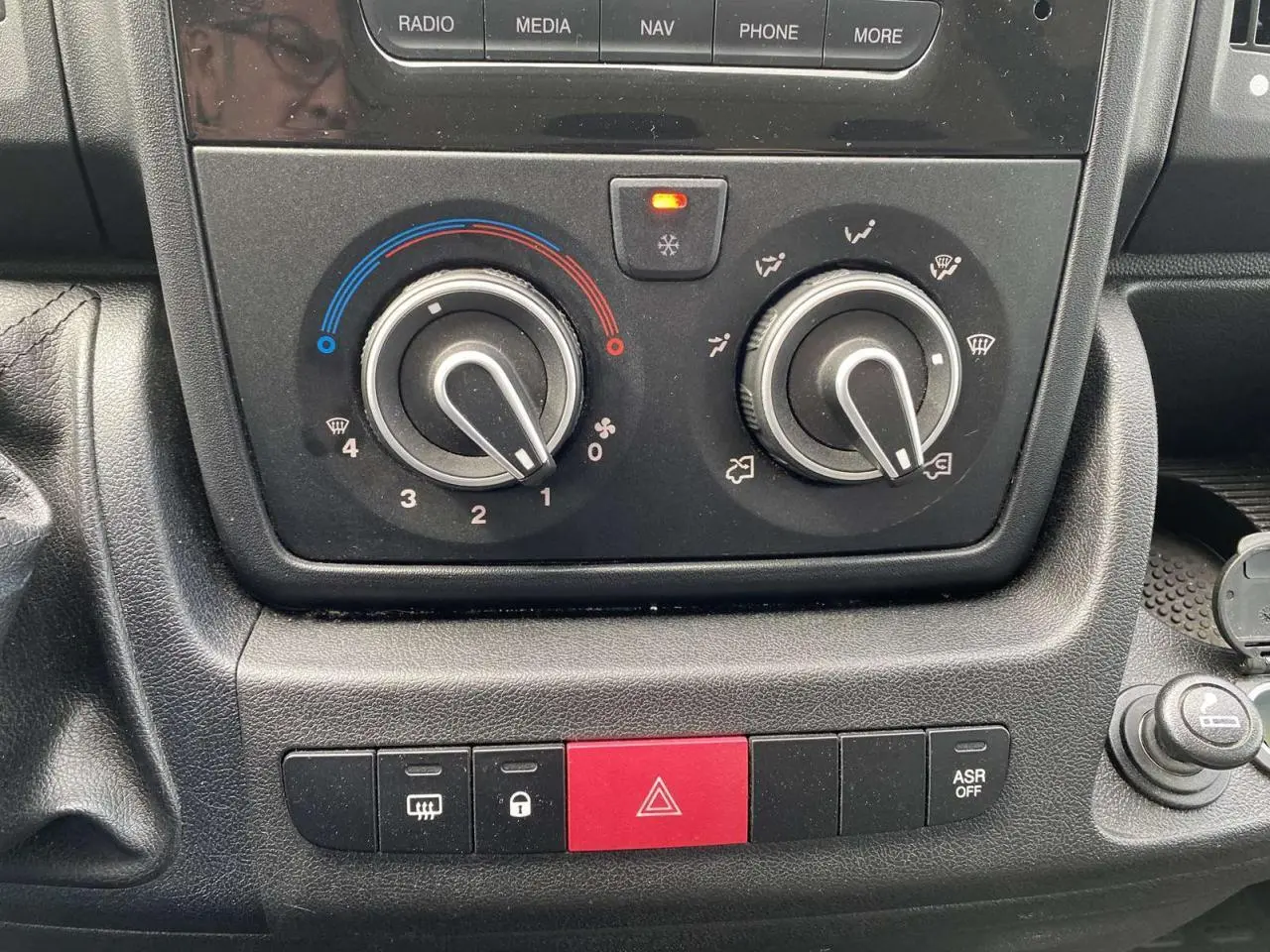 Gros plan sur les commandes de climatisation et les boutons de sécurité du tableau de bord du fourgon Opel Movano blanc.