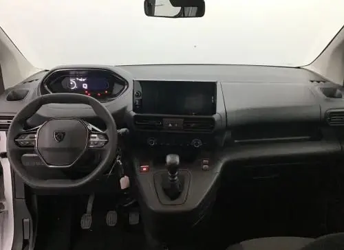 Vue frontale de l'intérieur noir du Peugeot Rifter 2025, avec volant compact, tableau de bord numérique et levier de vitesses manuel.