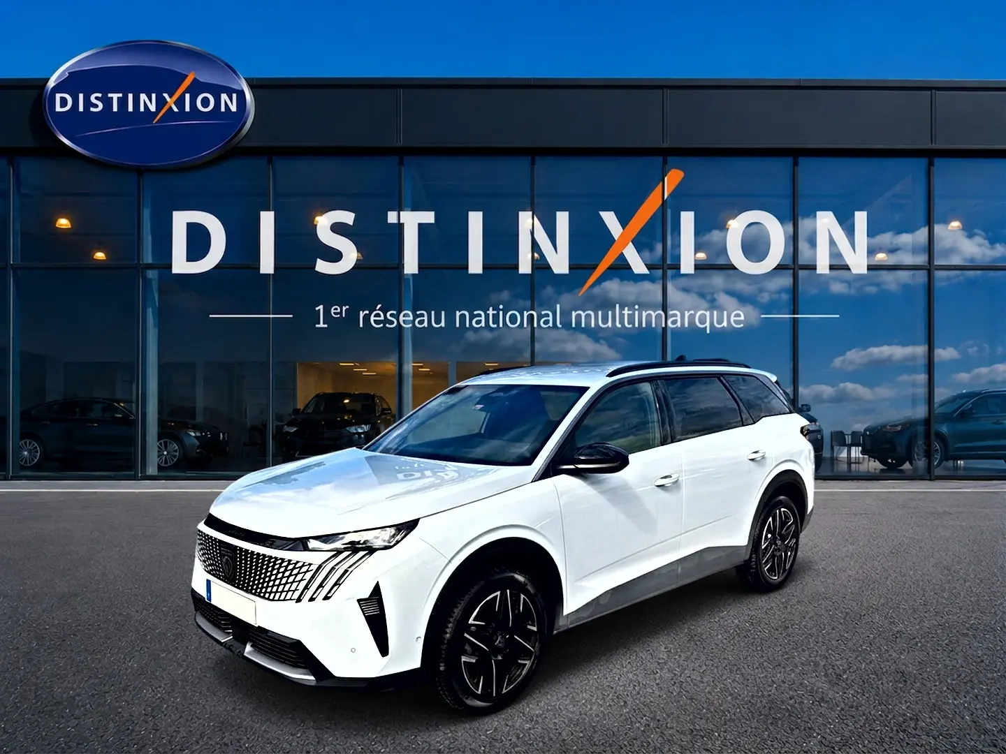 Peugeot 5008 blanc en 3/4 avant droit, avec jantes alu noires et toit noir, devant une vitrine Distinxion.