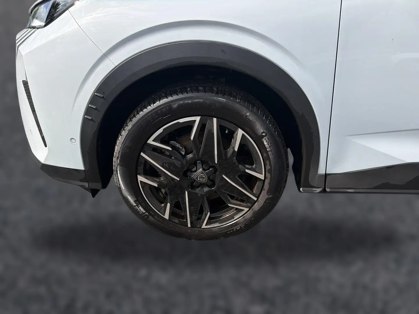 Gros plan sur la roue avant droite d’un Peugeot 5008 blanc avec jante alliage noire et argentée.