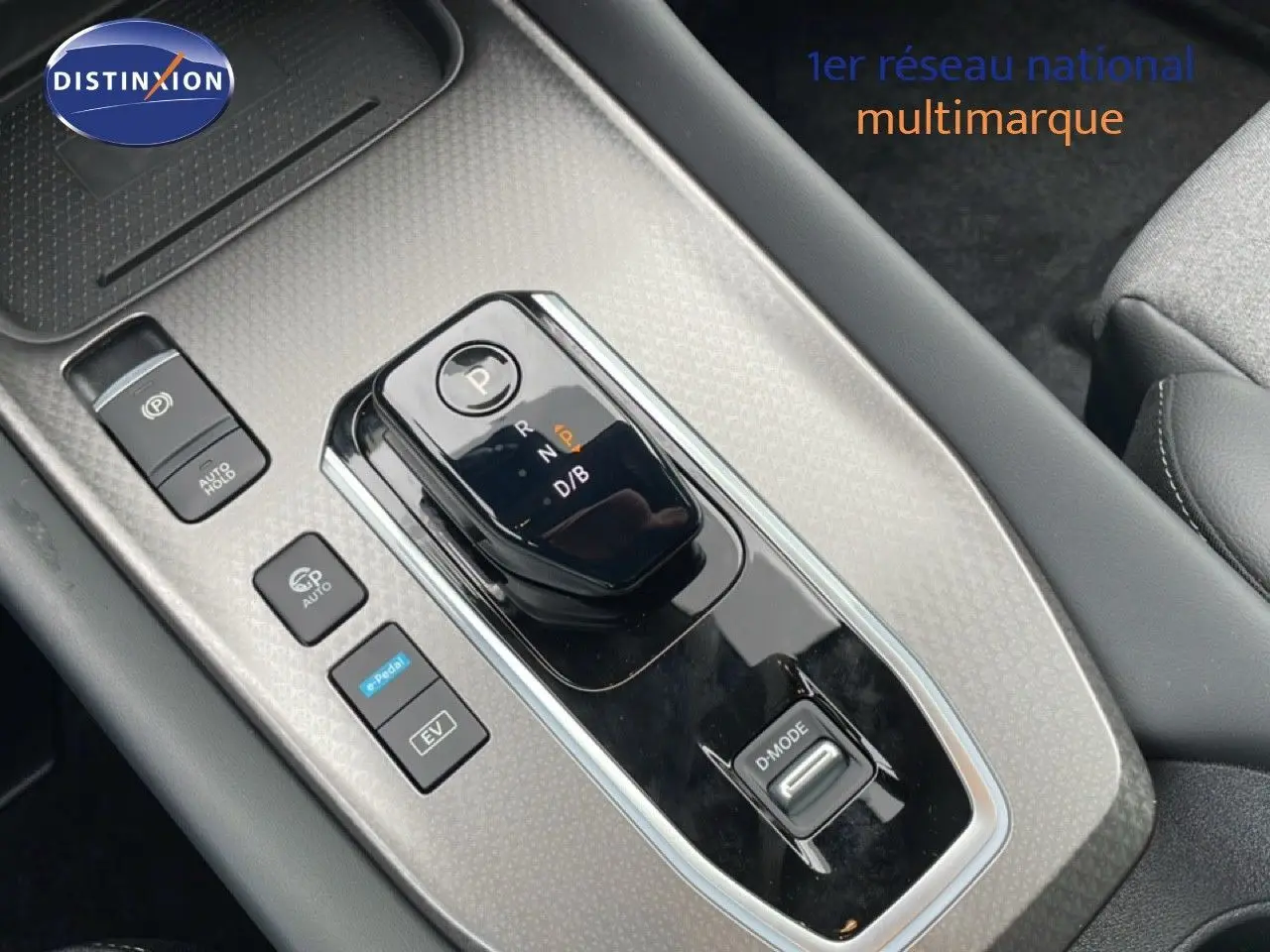 Vue rapprochée de la console centrale du Nissan Qashqai gris Squale Metal, avec levier de vitesse automatique et commandes hybrides.