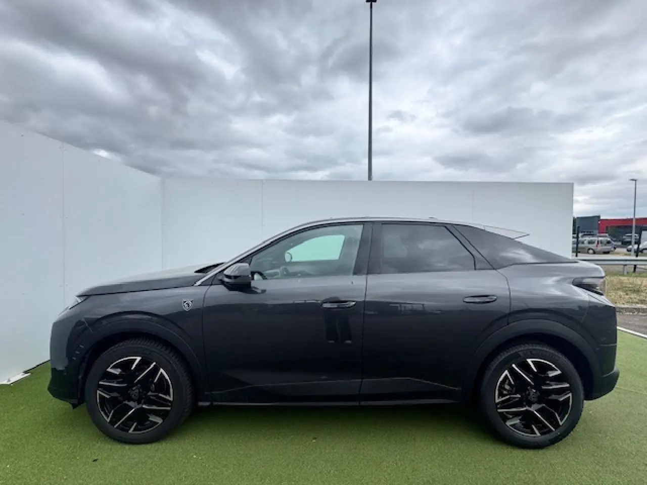 Profil côté gauche du Peugeot 3008 gris titane avec toit noir, jantes alliage noires et détails modernes.