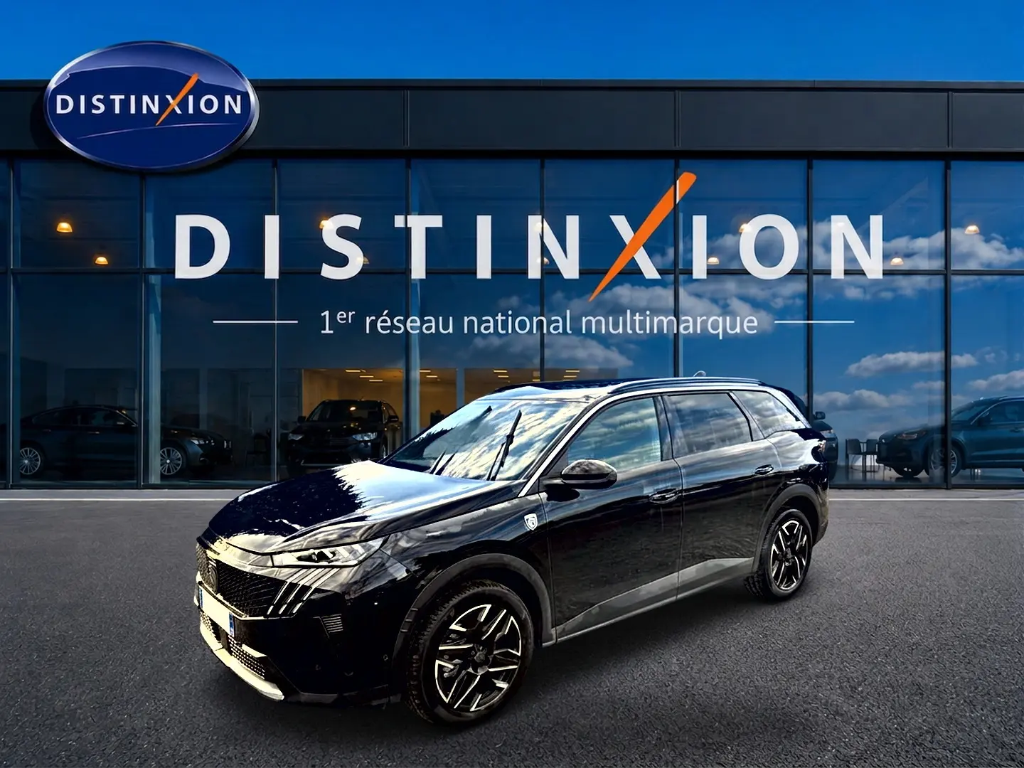 Peugeot 5008 Hybrid 145 GT noir en 3/4 avant droit, avec jantes alu et vitres surteintées devant un showroom Distinxion.