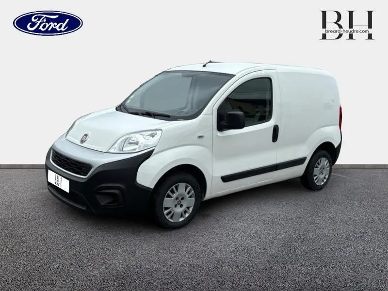 Fourgon FIAT Fiorino blanc vu en 3/4 avant droit, avec pare-chocs noir et porte latérale droite visible.