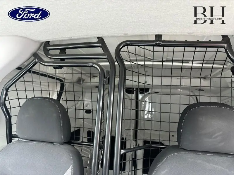 Intérieur du FIAT Fiorino blanc 2018 vu de l'avant, montrant la cloison modulable en grille entre cabine et espace de chargement.