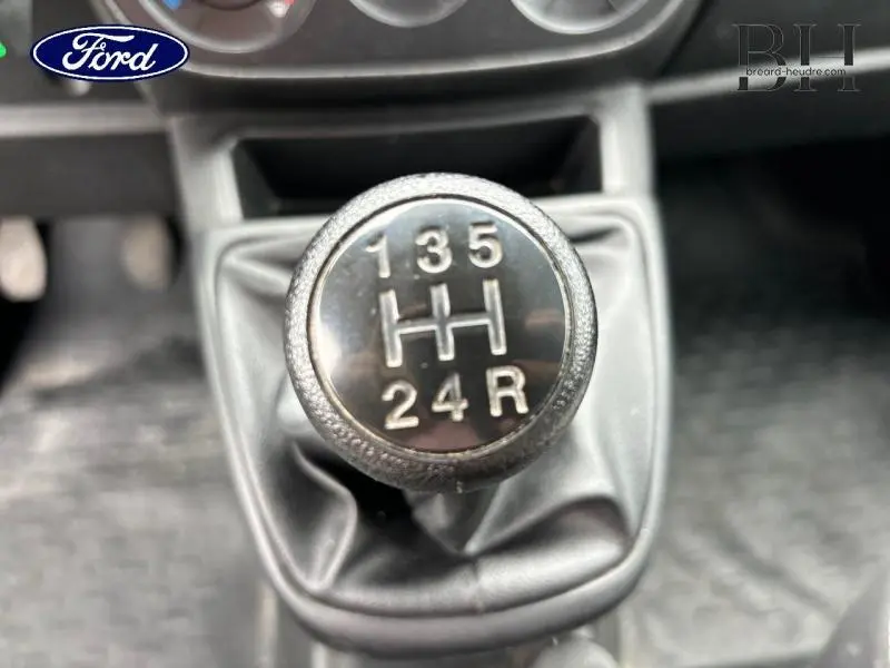 Gros plan sur le levier de vitesses manuel noir du Fiat Fiorino blanc, montrant la grille des 5 rapports et la marche arrière.