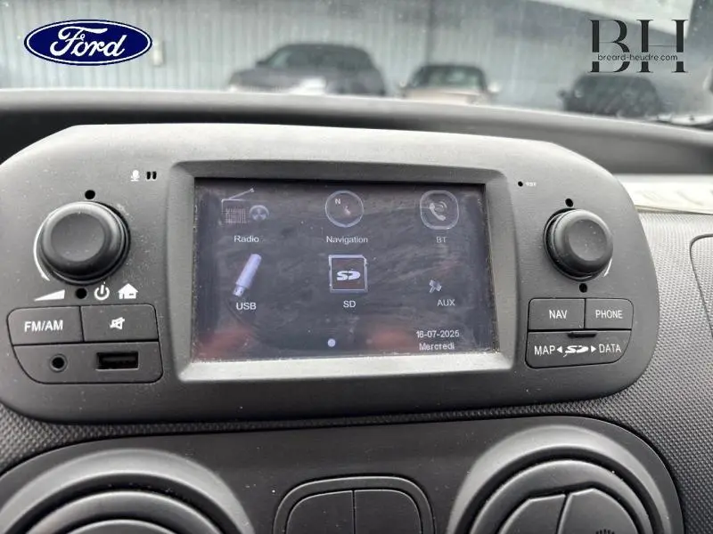 Vue rapprochée de l'écran tactile central du tableau de bord du Fiat Fiorino blanc de 2018 avec commandes audio et navigation.